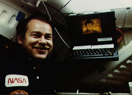 John Creighton posando junto al GRid Compass 1101 en una misión del transbordador espacial Discovery en 1985